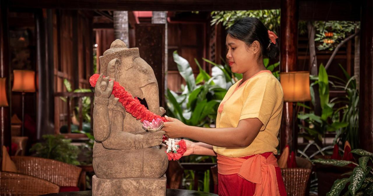 Angkor Village Hotel - Small Luxury Hotels Of The World Siem Reap Dış mekan fotoğraf A woman in Thailand, wearing traditional Thai clothing, garlands a statue of the Hindu god Ganesha.